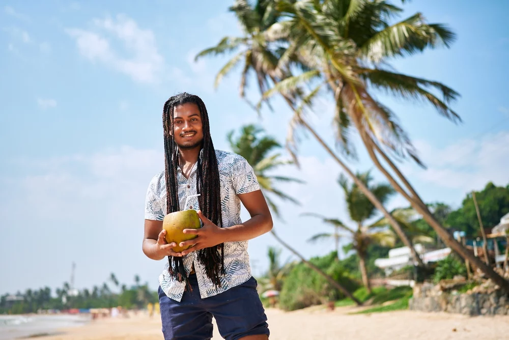A solo traveler enjoys a coconut drink on the beach in Turks and Caicos