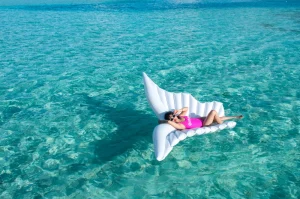 A solo traveler lounges on a pool float in the crystal clear waters of Turks and Caicos.